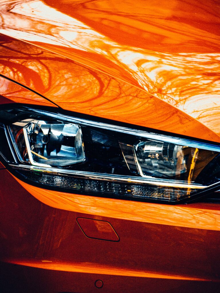 closeup shot of the right headlight of an orange modern car